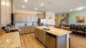 A modern kitchen with granite countertops, stainless steel appliances, and wooden flooring.