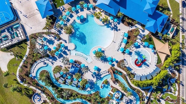 An aerial view of a resort with a central pool, multiple water slides, and sun loungers.