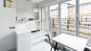 Ett modernt kök med vita köksskåp, en inbyggd ugn och en matplats med bord och stolar.