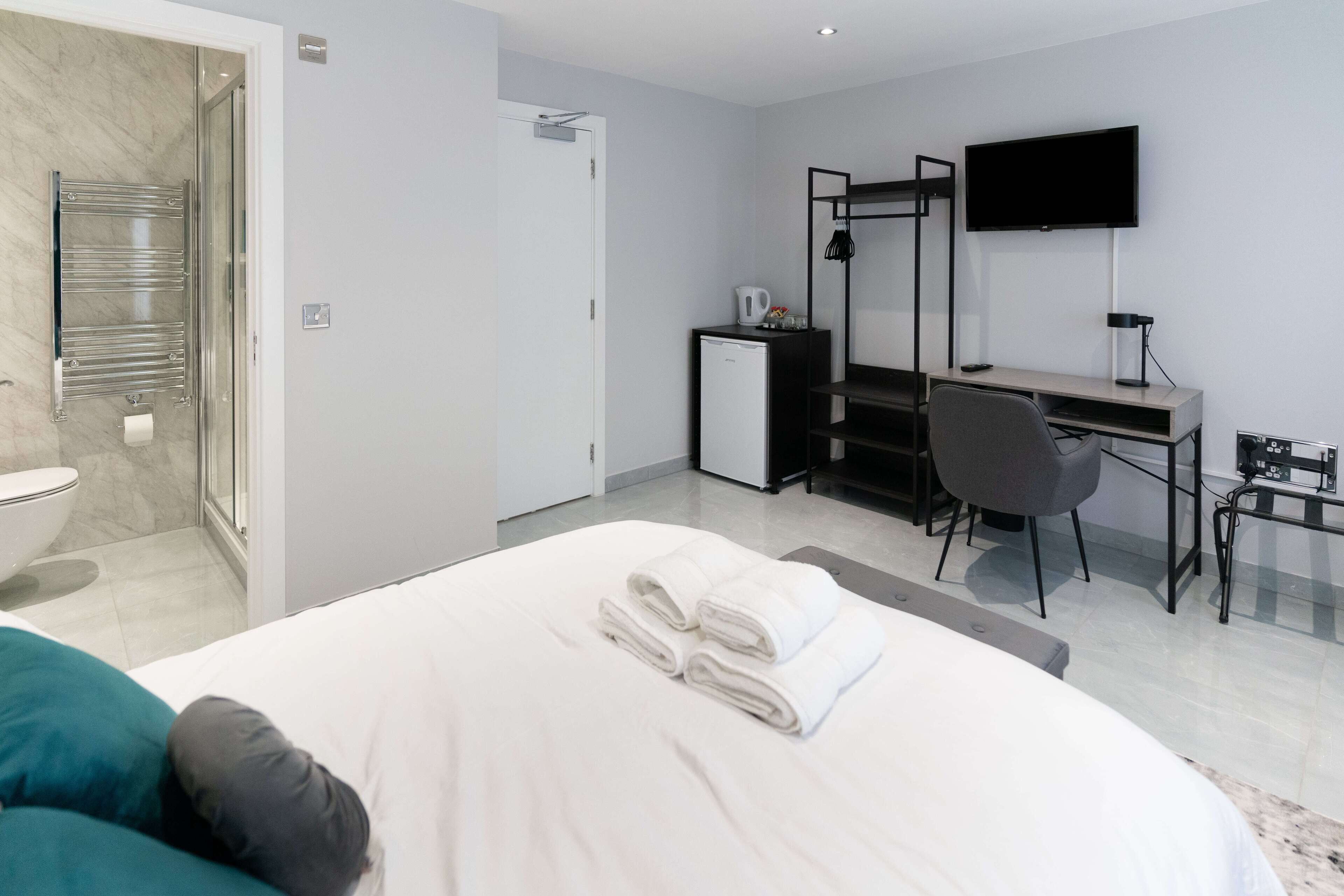 Une chambre d’hôtel équipée d’un lit, d’un bureau, d’une chaise, d’une télévision et d’une petite kitchenette.