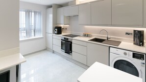 Ett modernt kök med inbyggda vitvaror, diskmaskin och tvättmaskin.