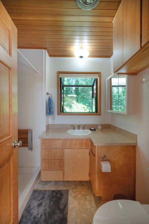 Une salle de bain avec des meubles en bois, un lavabo, une fenêtre et des toilettes.