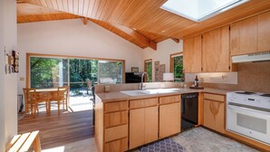 A modern kitchen with wooden cabinets, a built-in dishwasher, and a large island with a sink. - McKenzie Bridge River's Edge Retreat, a cozy cabin on over two acres (McKenzie Bridge)