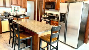 A kitchen with wooden cabinets, a granite countertop, a stainless steel refrigerator, and a microwave. - Cozy First Floor Apartment. Located in a quiet neighborhood. (Chicopee)