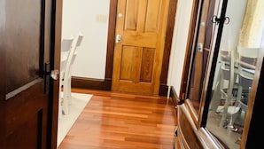 A hallway with wooden flooring, a wooden door, and a large mirror cabinet. - Cozy First Floor Apartment. Located in a quiet neighborhood. (Chicopee)