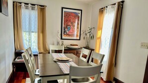 A dining area with a wooden table, white chairs, and a striped placemat. - Cozy First Floor Apartment. Located in a quiet neighborhood. (Chicopee)