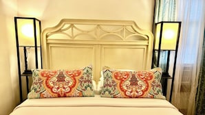 A bed with a white headboard, two decorative pillows, an orange quilt, and two wall-mounted lamps. - Cozy First Floor Apartment. Located in a quiet neighborhood. (Chicopee)