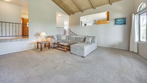 A spacious living room with a high ceiling, a sectional sofa, a coffee table, and a lamp. - Secluded Waimea Hideaway w/ Lanai & Views! (Waimea)