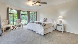A bedroom with a large bed, two armchairs, a nightstand, a ceiling fan, and large windows. - Secluded Waimea Hideaway w/ Lanai & Views! (Waimea)