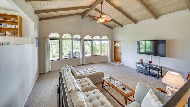 A spacious living room with a high ceiling, large windows, a sectional sofa, a television, and a fireplace. - Secluded Waimea Hideaway w/ Lanai & Views! (Waimea)