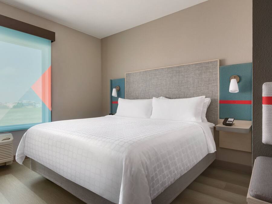 Een hotelkamer met een groot bed, een nachtkastje met een telefoon en een raam met uitzicht.