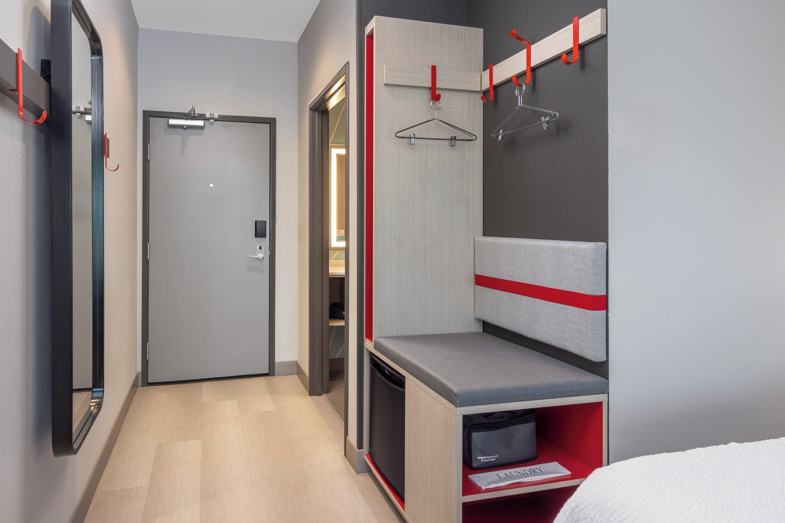 Una habitación de hotel moderna con vestidor, cama y escritorio empotrado.
