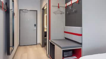 Una habitación de hotel moderna con vestidor, cama y escritorio empotrado.