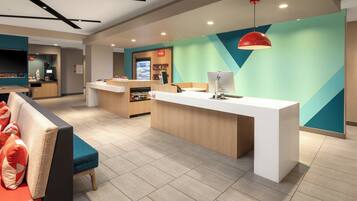 A modern reception area with a counter, seating, and a coffee machine.