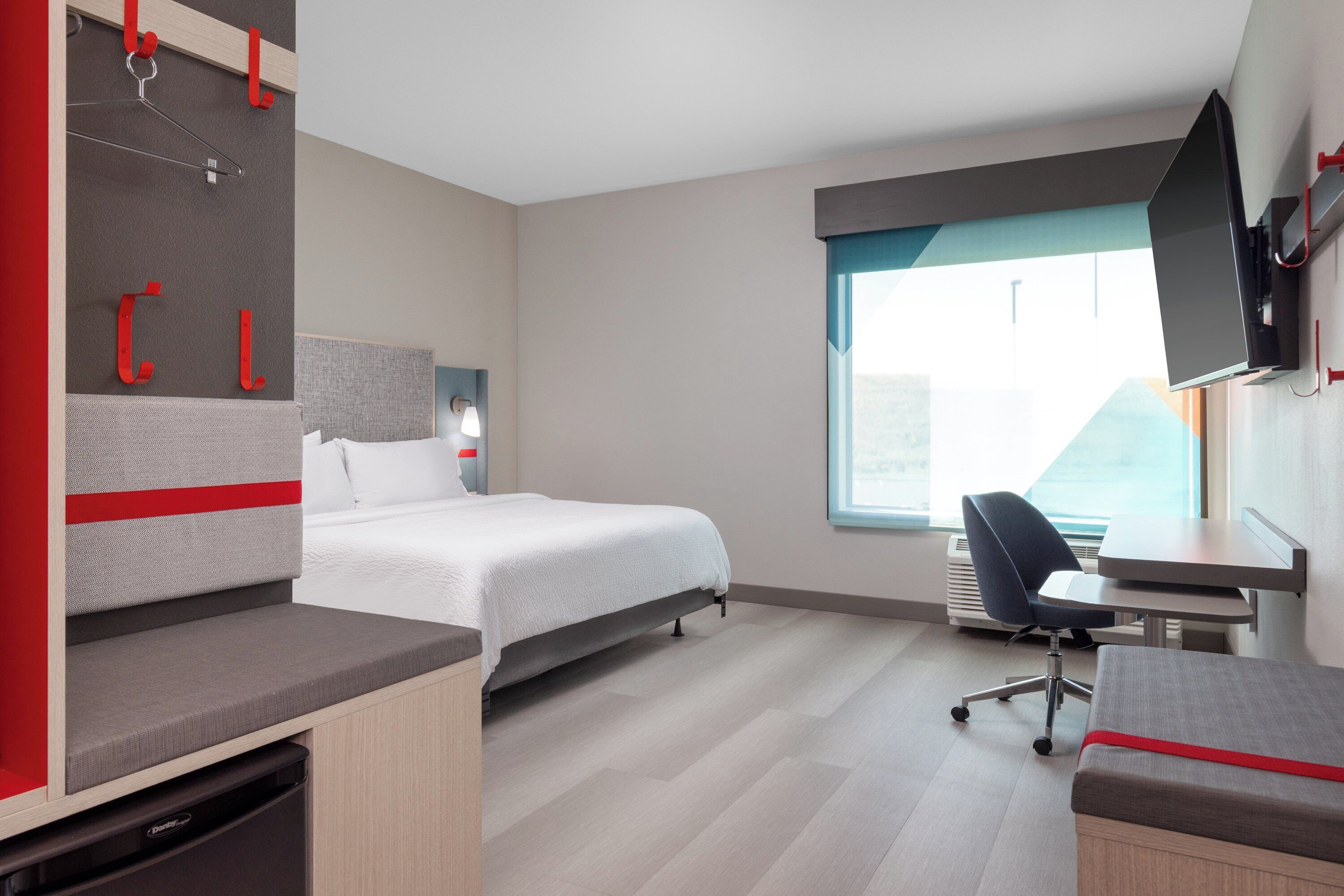 A modern hotel room with a bed, desk, and seating area.