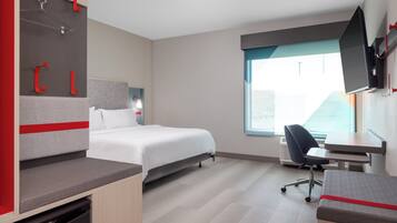 A modern hotel room with a bed, desk, and seating area.