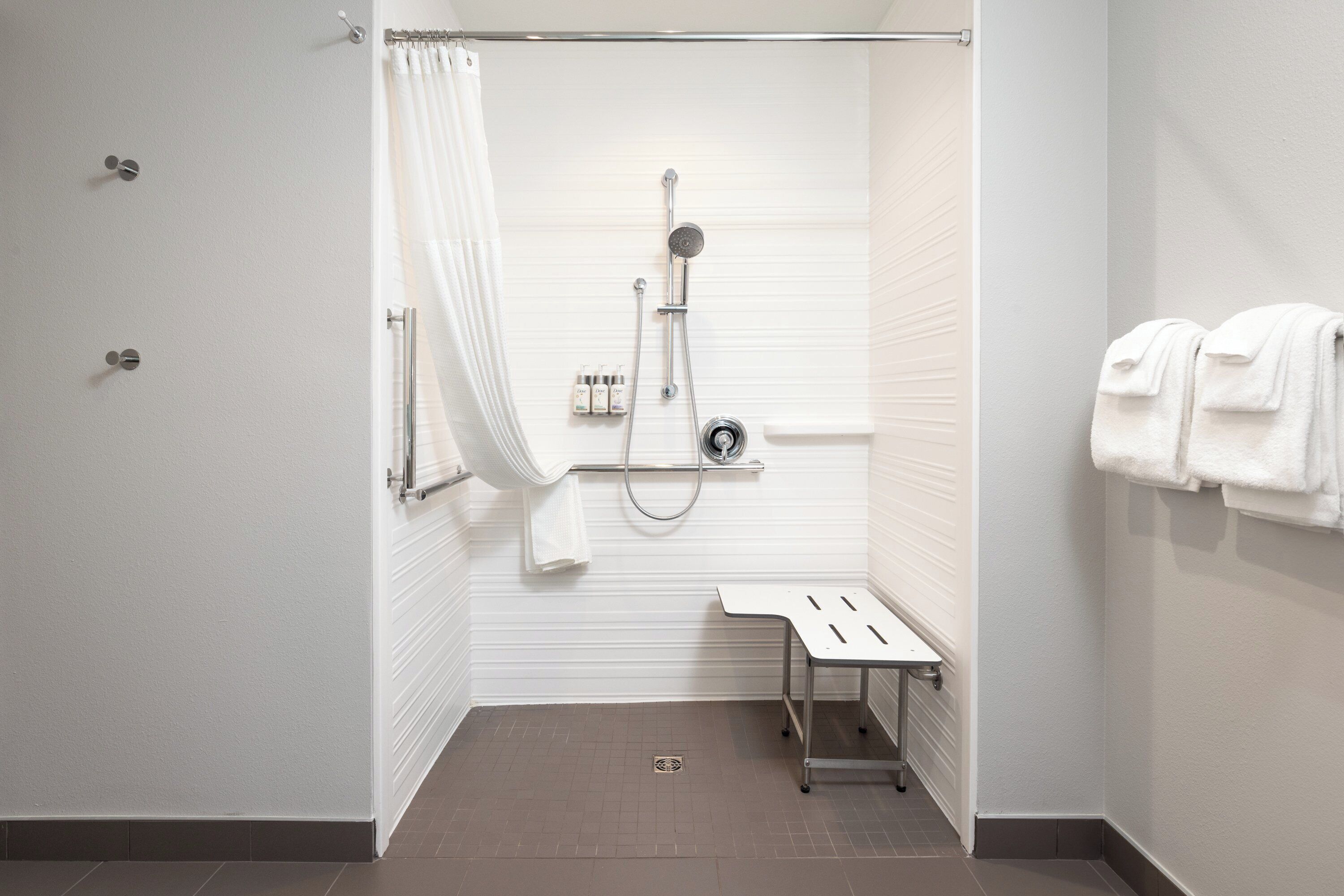 Een moderne badkamer met een douche, een klein tafeltje en een handdoekhouder.