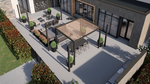 Un patio al aire libre con mobiliario y macetas, rodeado por un edificio con amplios ventanales y un muro de piedra.