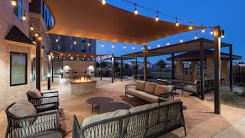 An outdoor patio area with seating, a fire feature, and string lights.
