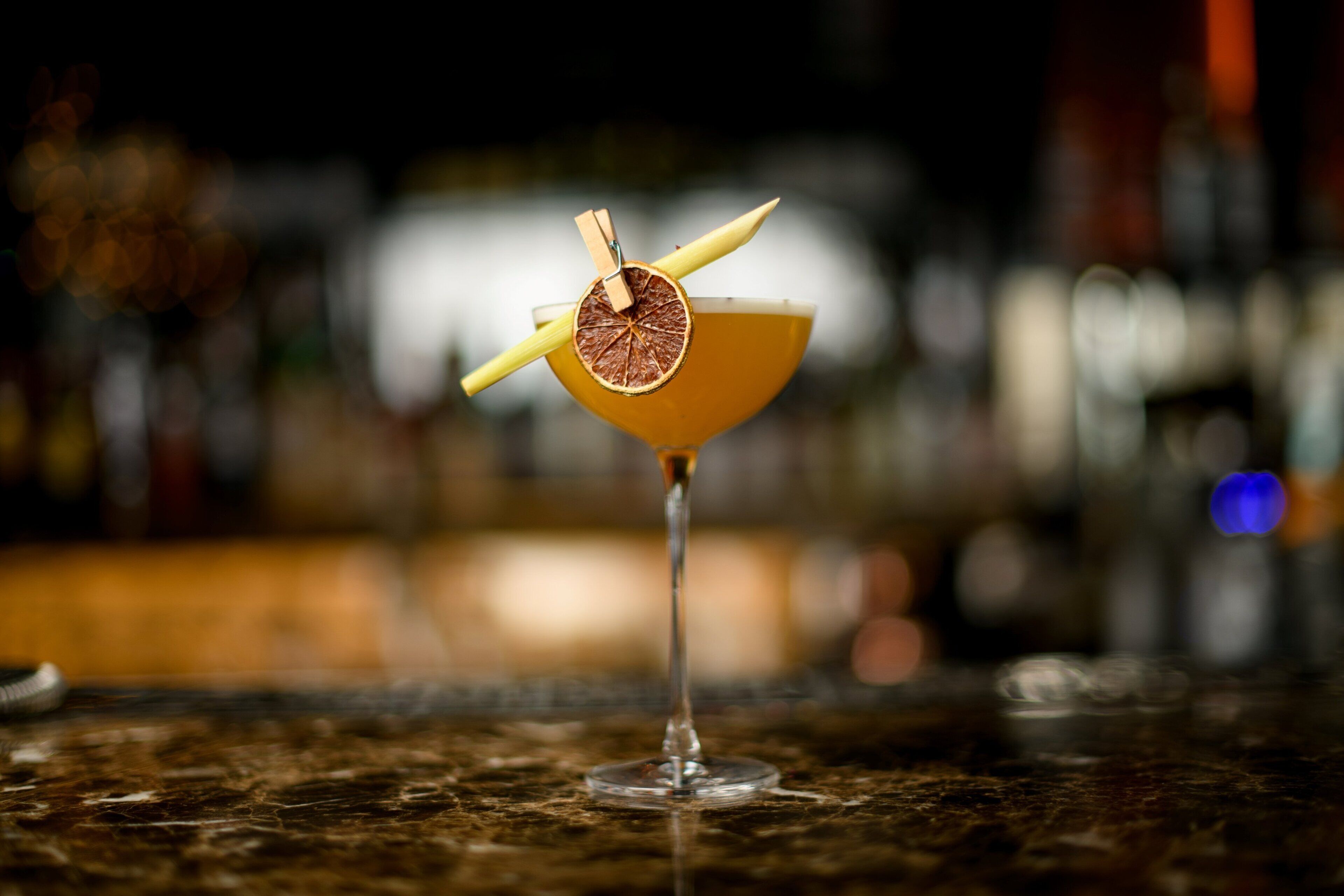 A cocktail with a citrus garnish on a bar counter.