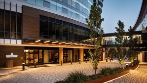 A modern hotel entrance with a glass facade, outdoor seating area, and a landscaped garden. - InterContinental Seattle Bellevue, by IHG (Bellevue)