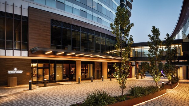 A modern hotel entrance with a glass facade, outdoor seating area, and a landscaped garden. - InterContinental Seattle Bellevue, by IHG (Bellevue)