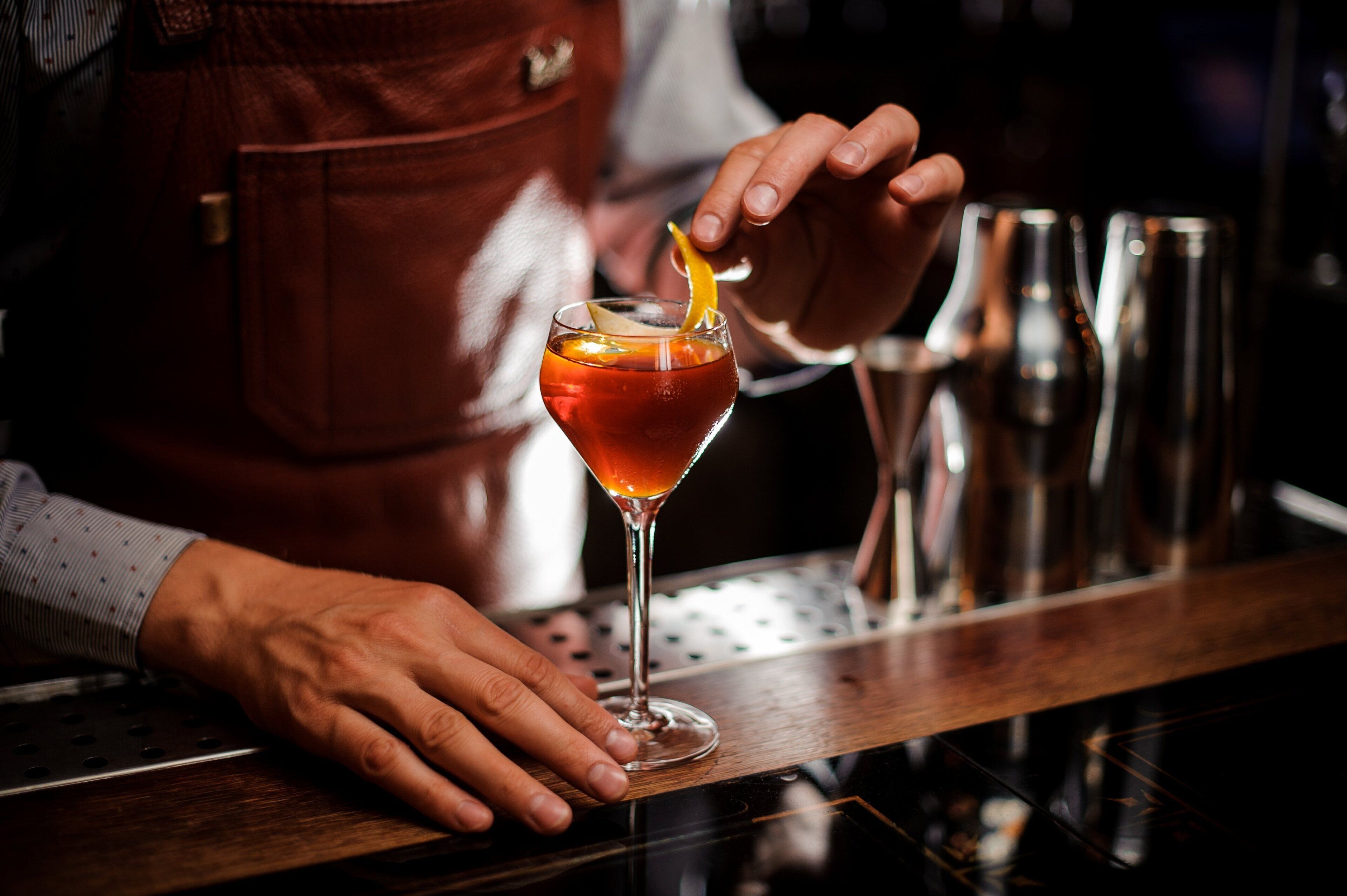 Un barman preparant un còctel amb una taronja com a guarnició.