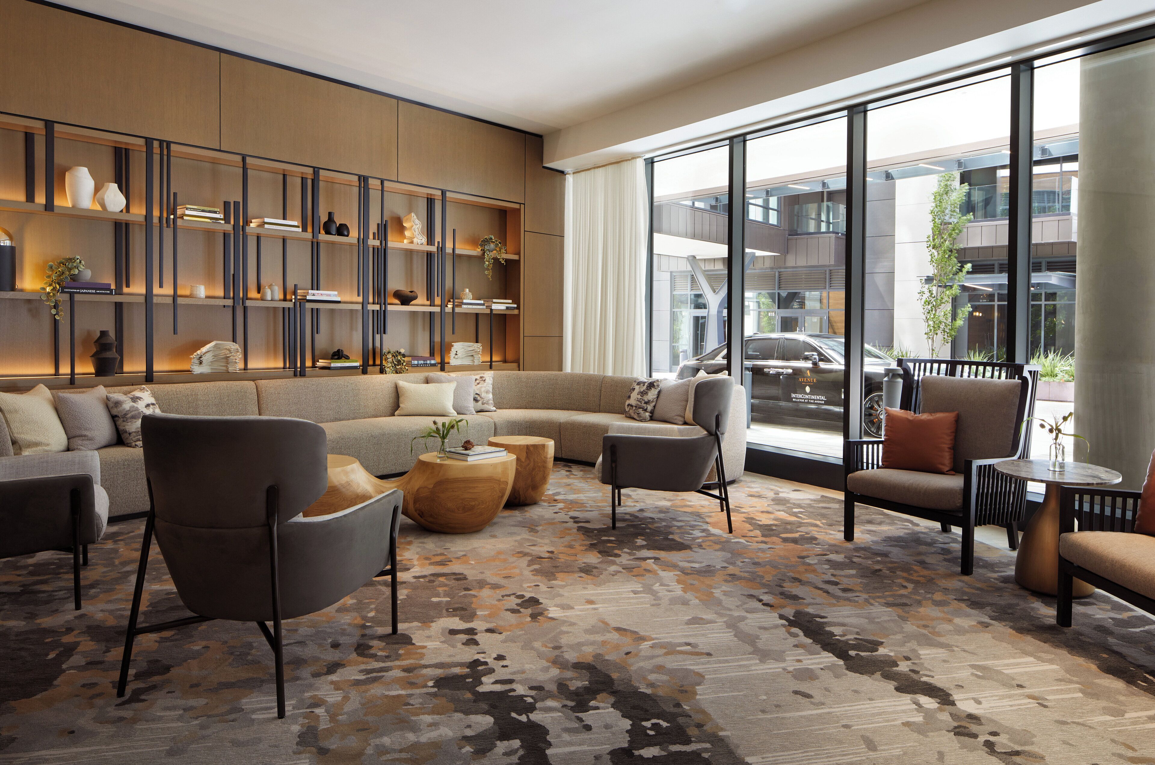 A modern living room with a sectional sofa, armchairs, a coffee table, and a bookshelf.