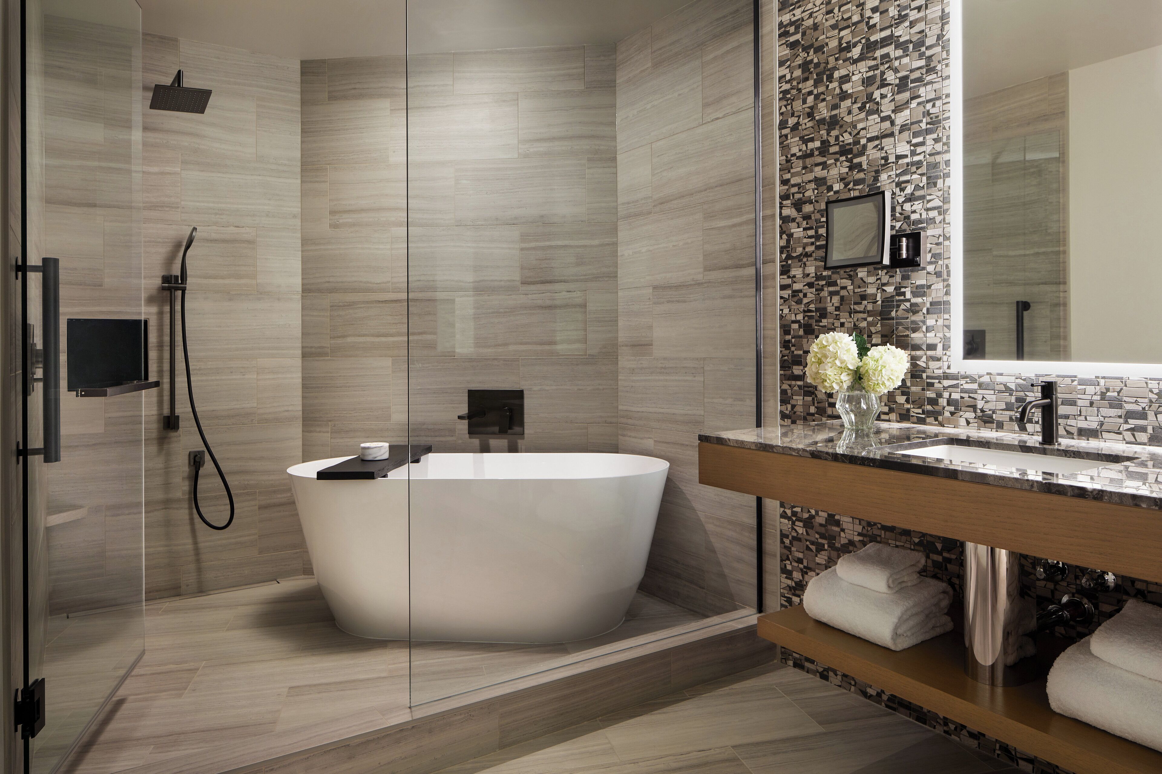 A modern bathroom with a freestanding bathtub, a glass-enclosed shower, and a vanity with a mirror and towel rack.