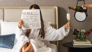 A person reading a newspaper, holding a champagne glass, and another person pouring champagne. - InterContinental Seattle Bellevue, by IHG (Bellevue)