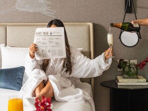 A person reading a newspaper, holding a champagne glass, and another person pouring champagne. - InterContinental Seattle Bellevue, by IHG (Bellevue)