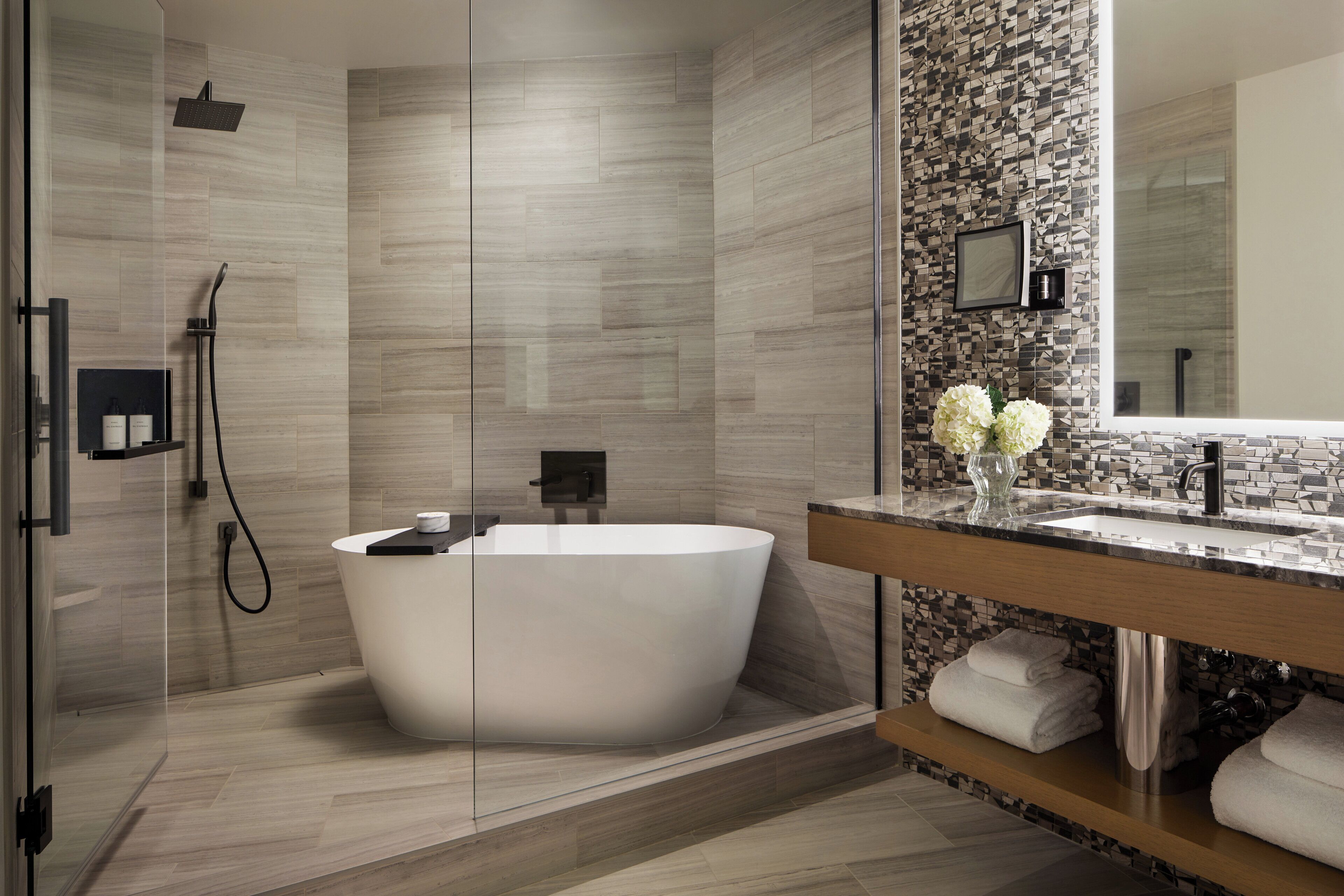 A modern bathroom with a freestanding bathtub, a glass-enclosed shower, and a vanity with a mirror.