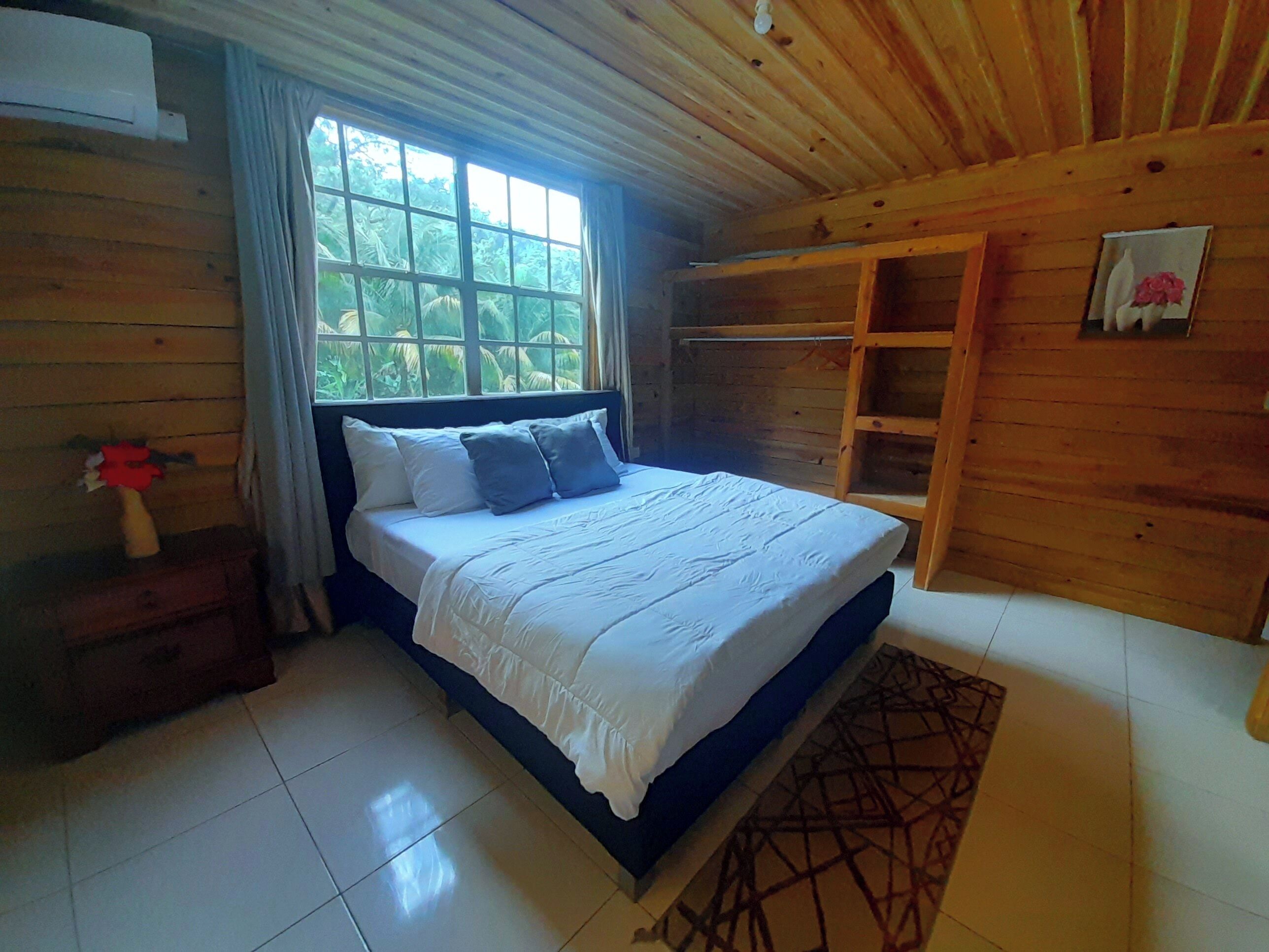 A wooden-paneled bedroom with a bed, a window, and a wooden wardrobe.