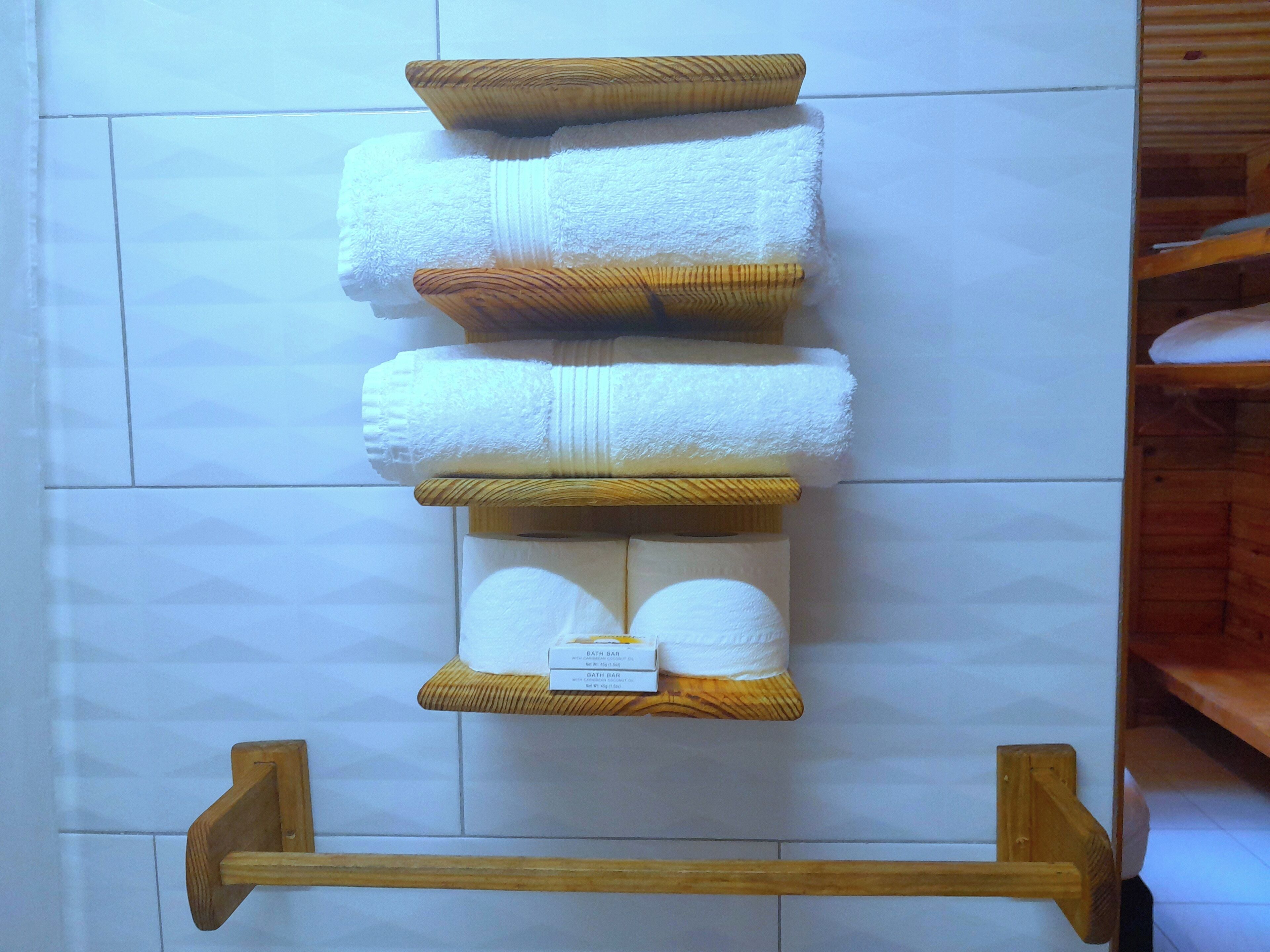 Un baño con un perchero de madera que sostiene varias toallas blancas y dos jabones de baño.