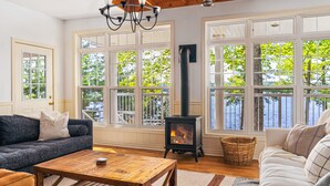 A cozy living room with a fireplace, large windows, and comfortable seating.