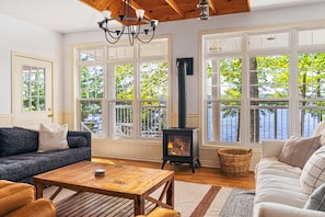 A cozy living room with a fireplace, large windows, and comfortable seating.