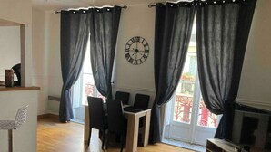 A living room with a dining area, a TV, and a clock on the wall.