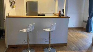 A modern kitchen with a central island, two bar stools, and a large mirror above the island.