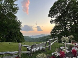 Un banc en bois dans un jardin, avec vue sur une chaîne de montagnes.