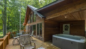 Eine Holzhütte mit einer Terrasse, einem Whirlpool und einer Feuerstelle.
