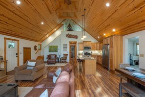 Un vaste espace de vie doté d’un haut plafond, de planchers en bois et d’une cuisine équipée d’appareils électroménagers modernes.