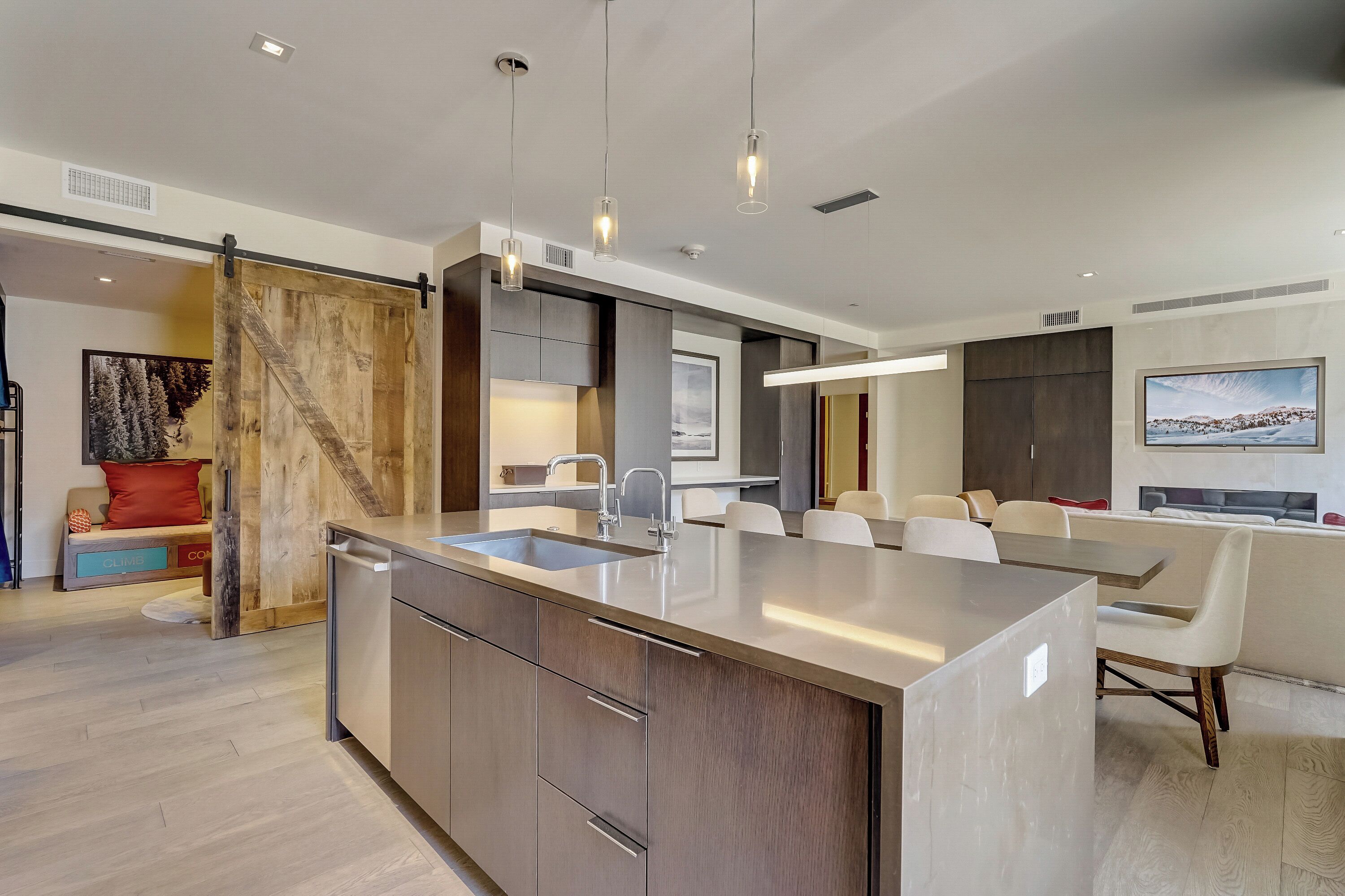 Una cocina moderna con una isla grande, electrodomésticos integrados e iluminación colgante.