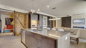 Una cocina moderna con una isla grande, electrodomésticos integrados e iluminación colgante.