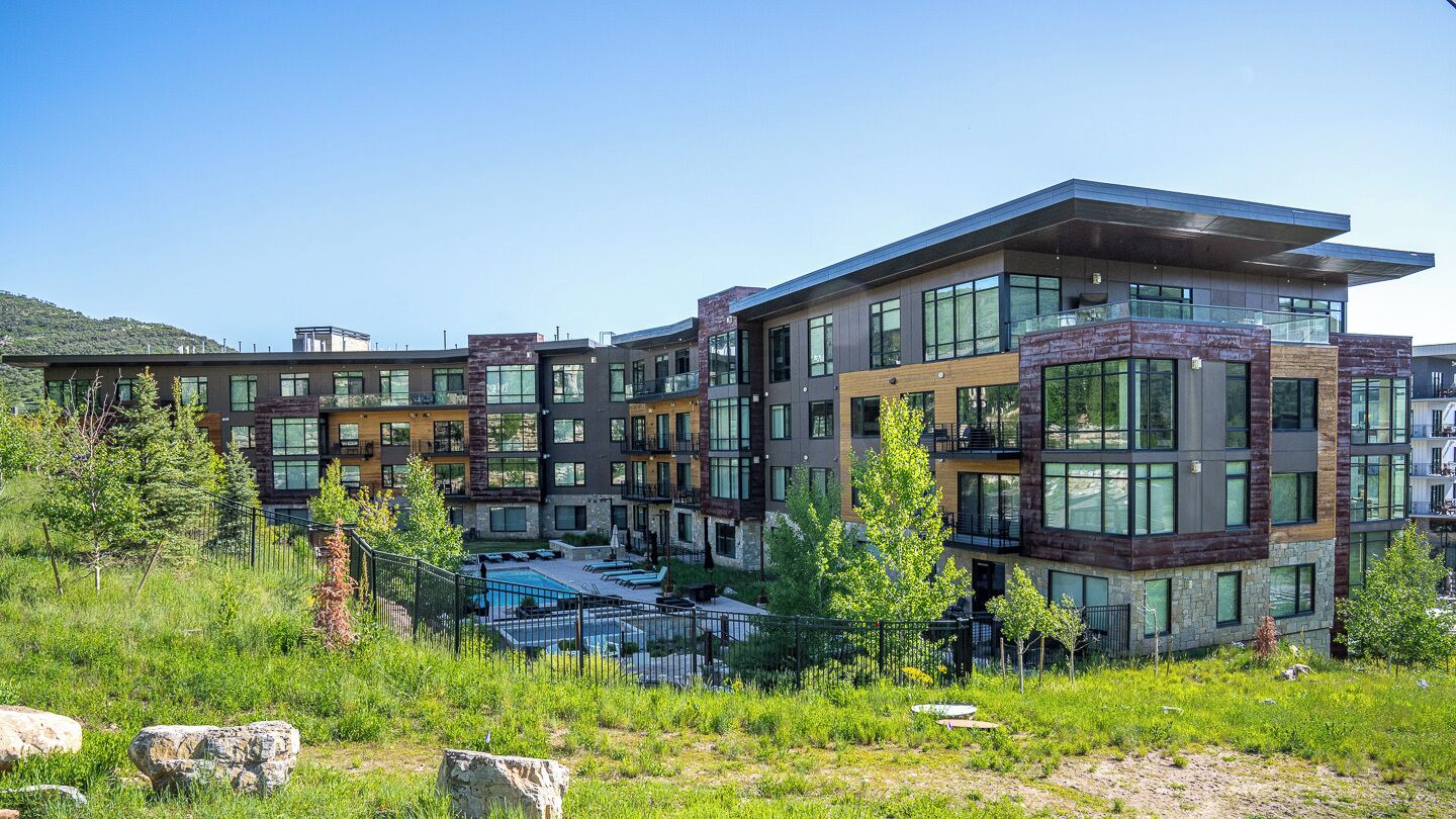 A modern multi-story residential building with large windows and a pool area.