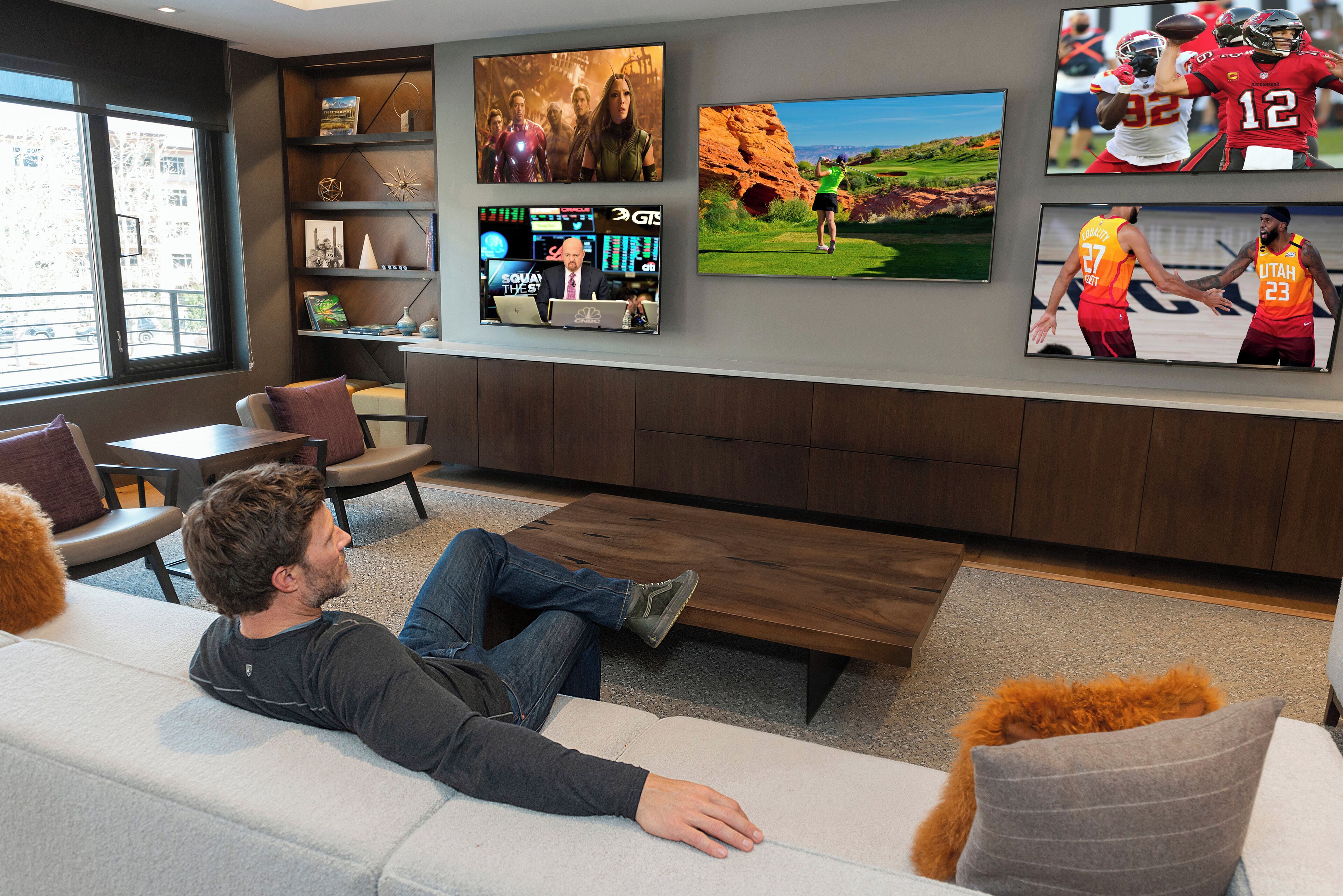 Un salon moderne avec un grand téléviseur à écran plat fixé au mur, un canapé et une table basse.