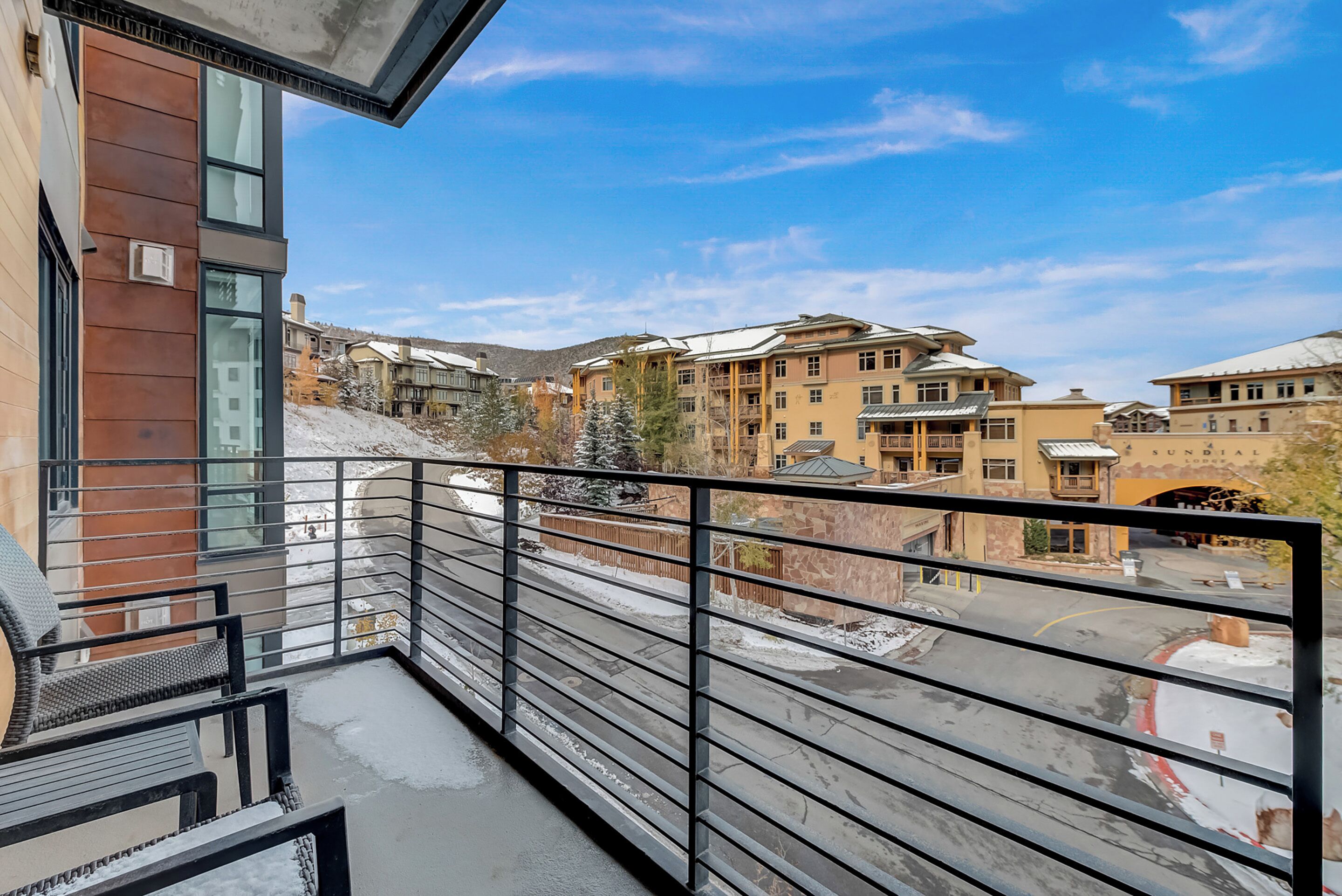 A balcony with a metal railing overlooking a snowy landscape and buildings.