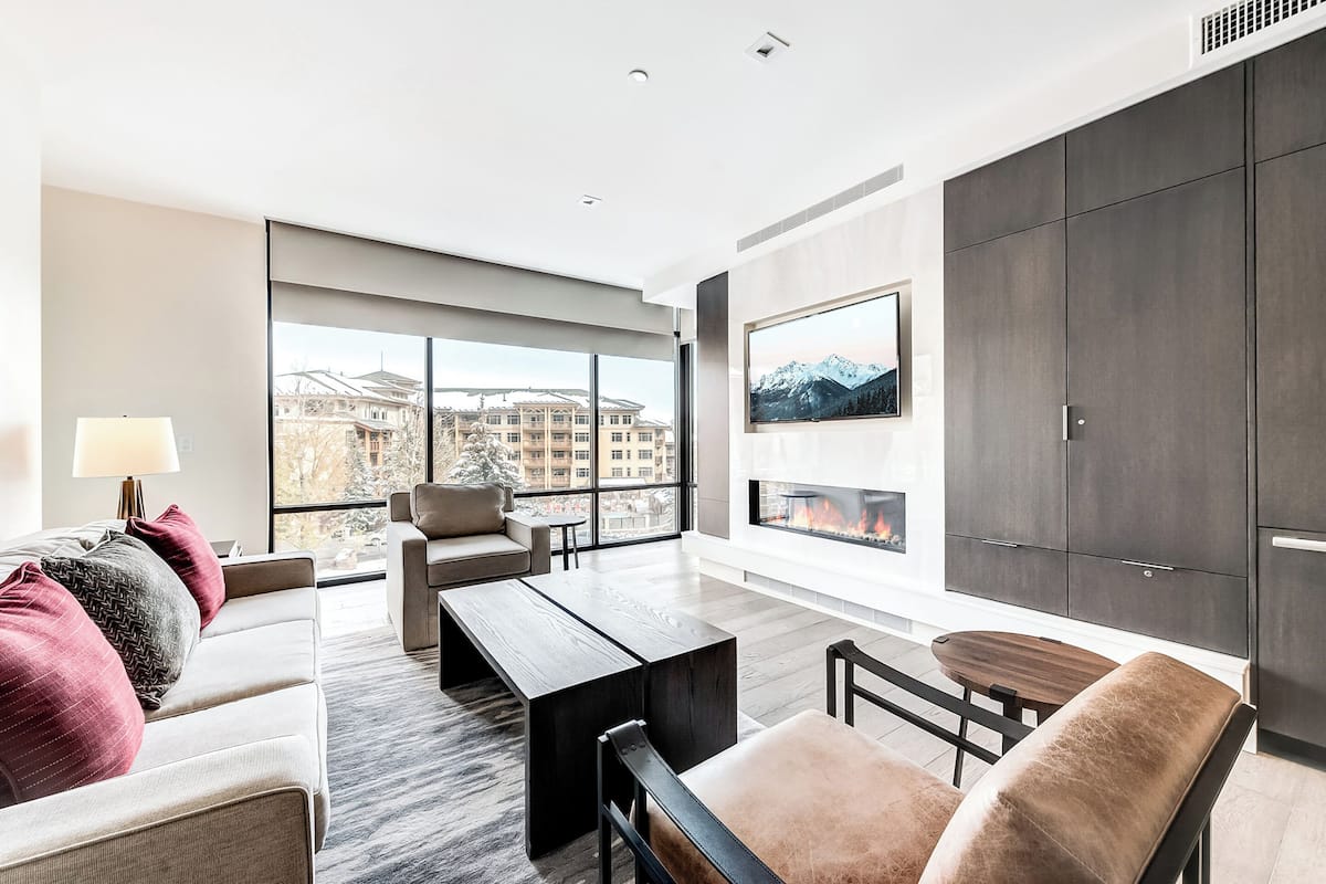 A modern living room with a sofa, chairs, a coffee table, and a fireplace.