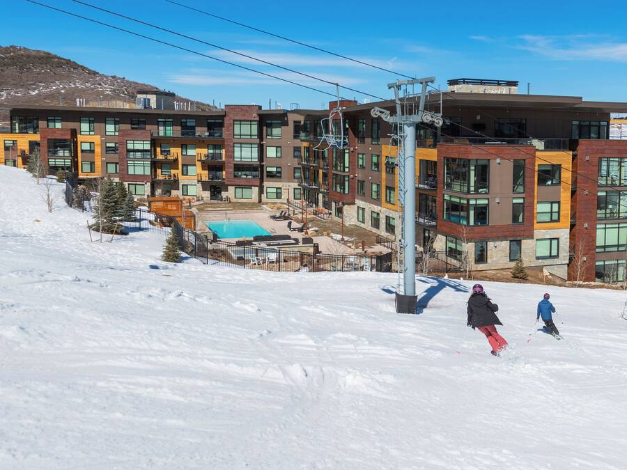 A modern multi-story hotel with a ski slope in the background.