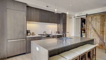 A modern kitchen with a large island, built-in appliances, and a rustic wooden door.