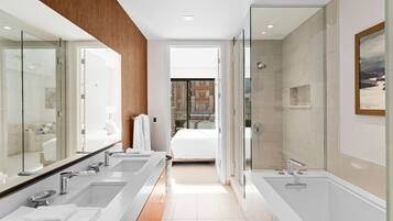Un baño moderno con lavamanos dobles, un espejo grande y ducha con mampara de vidrio.